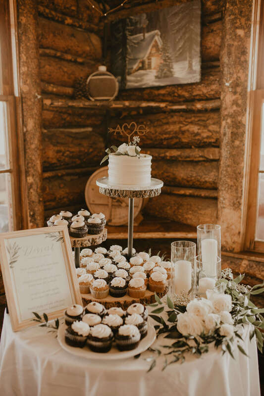 Wedding dessert table with white roses, eucalyptus, and candles