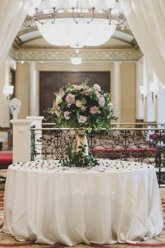 Wedding escort card table with floral centerpiece with light purple roses and greenery 