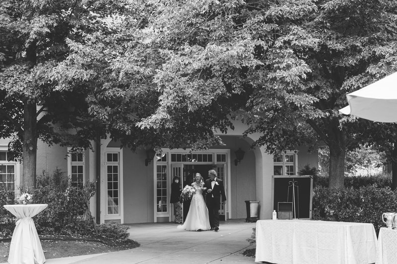 black and white photo of the bride walking with her father