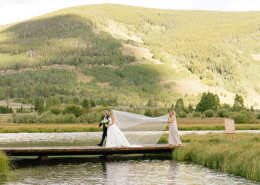 Bridesmaid holding a bride's veil at a wedding in Colorado