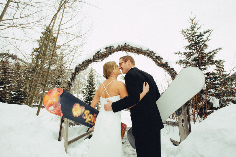 Bridge and groom kissing while holding snowboards