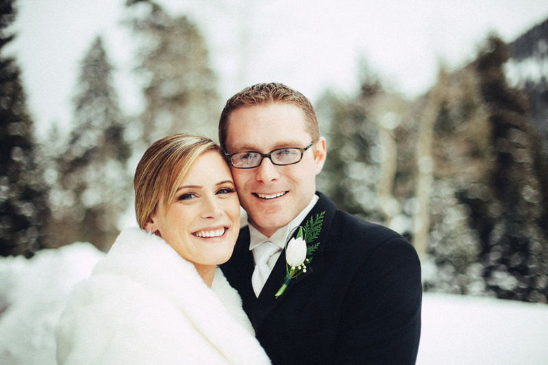 Bride and groom smiling outside in the snow covered mountains
