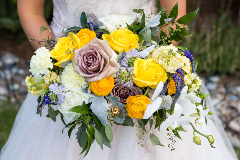 A bridal bouquet filled with yellow and lavender roses and white hydrangeas by Earth Tones Floral