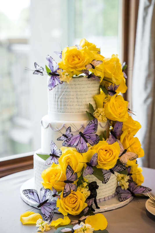 Wedding cake with calligraphy, yellow roses, and purple butterflies by The Makery Cake Co.