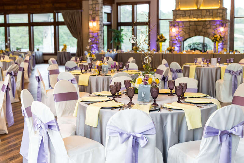 Purple satin chair sashes and tablecloths with yellow linen napkins at a wedding reception