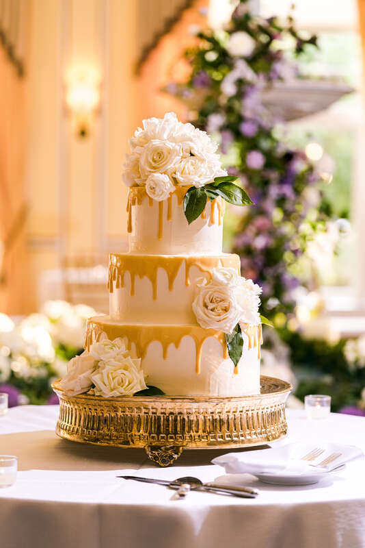 Drip cake topped with ivory roses for a wedding