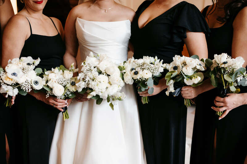 Bride and her bridesmaids holding white wedding bouquets filled with anemones, peonies, and gypsophila by SHEGROWS 