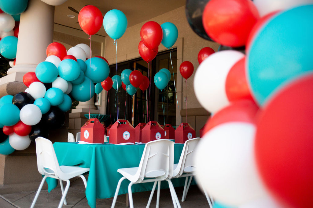 Kids tables and chairs with favor boxes and balloons