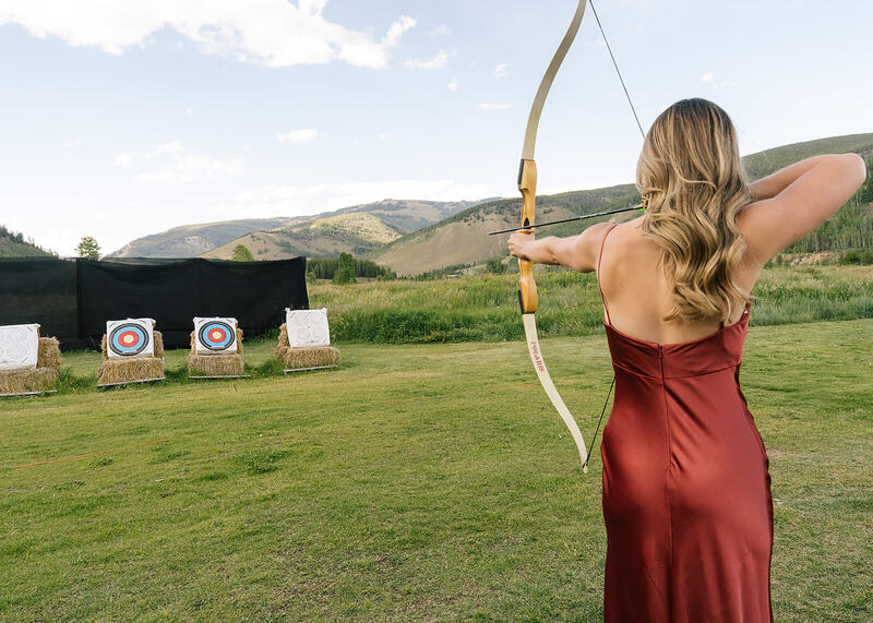 Wedding guest shooting a bow and arrow at a mountain wedding in Colorado