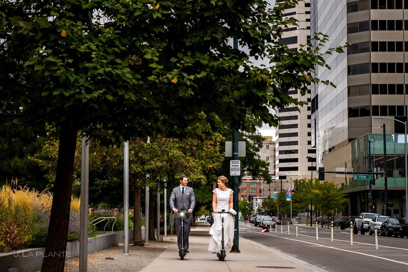 downtown denver wedding couple riding on electric scooters on downtown sidewalk