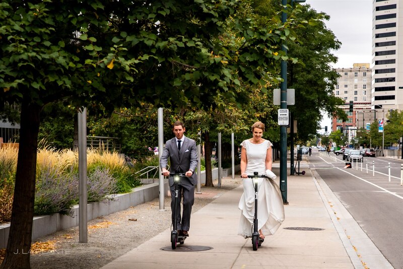 bride and groom riding towards the wedding photography on electric scooters