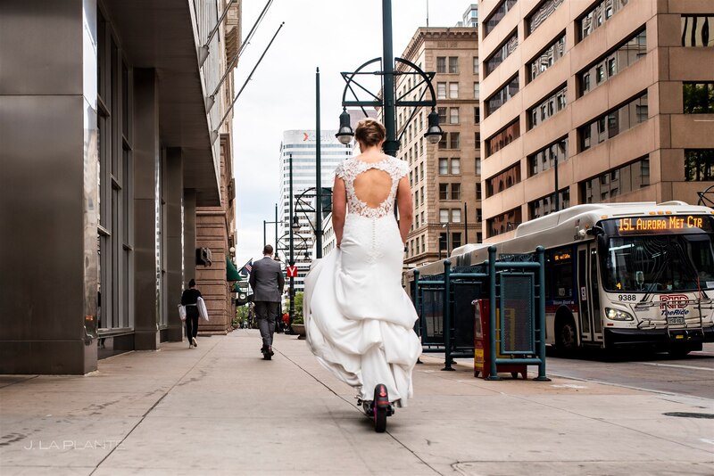 bride following groom in downtown denver wedding on electric scooters