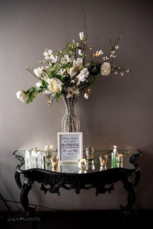 hand sanitizer station with candles, white rose floral bouquet and an unplugged wedding sign
