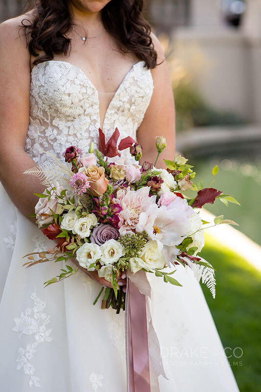 A bridal bouquet filled with blush peonies and purple roses by Southern Charm