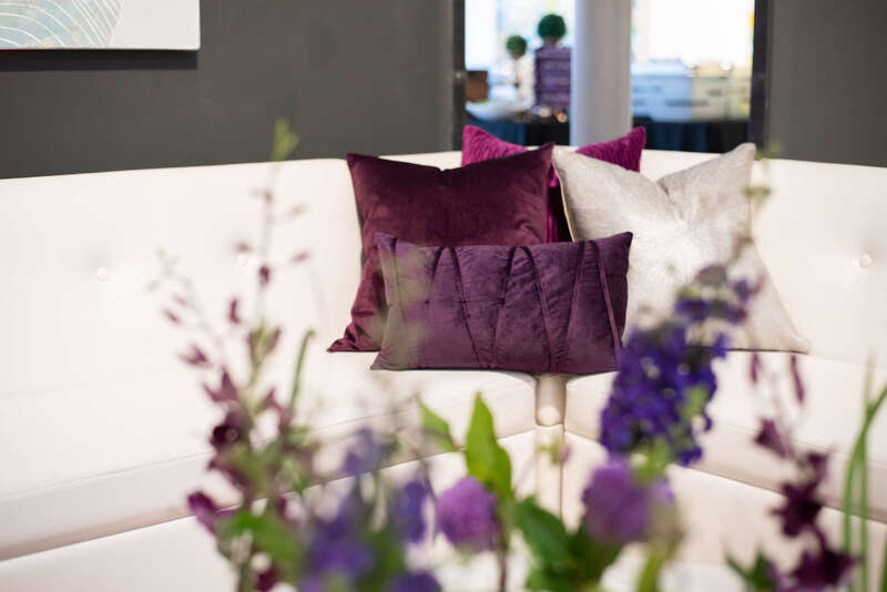 White lounge furniture with purple throw pillows by Bear Aesthetic