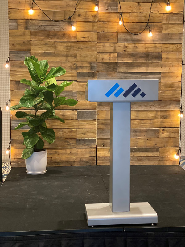 Custom logo podium with wooden backdrop with potted plant on staging