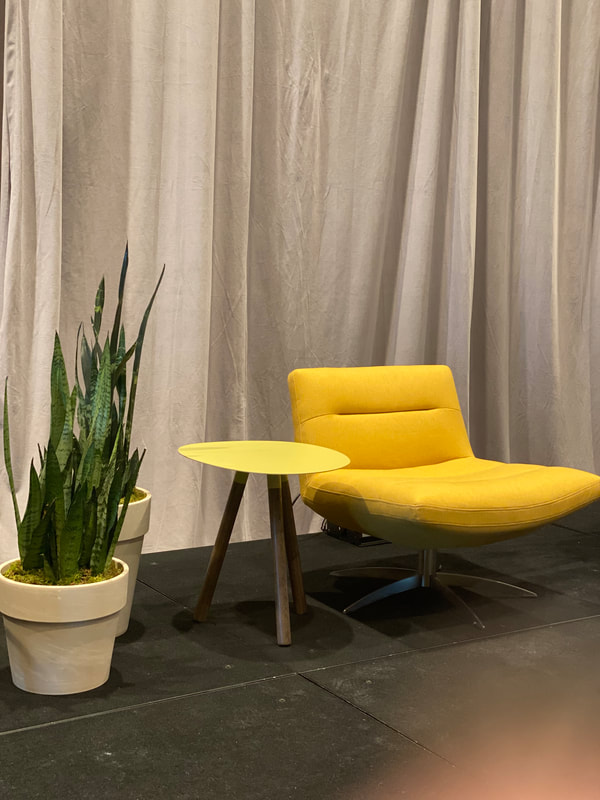 Armless yellow chair with small side table and potted plants