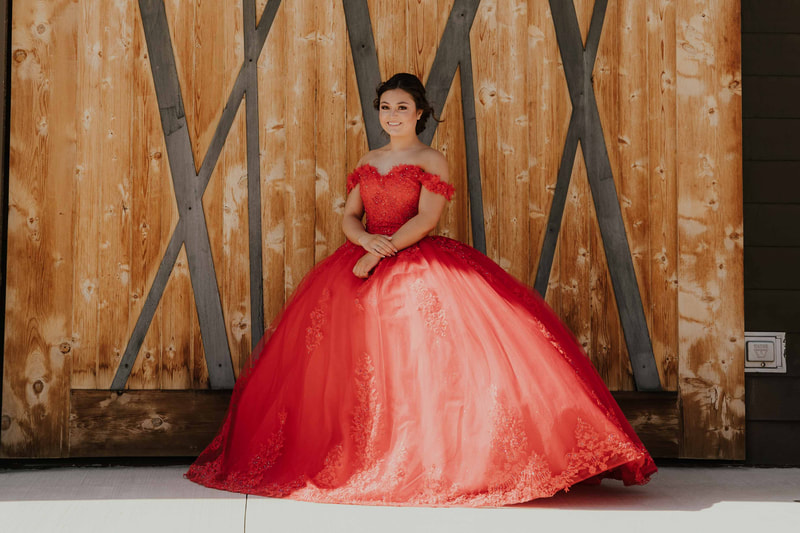 Girl in a red off-the-shoulder ballgown for her quinceañera