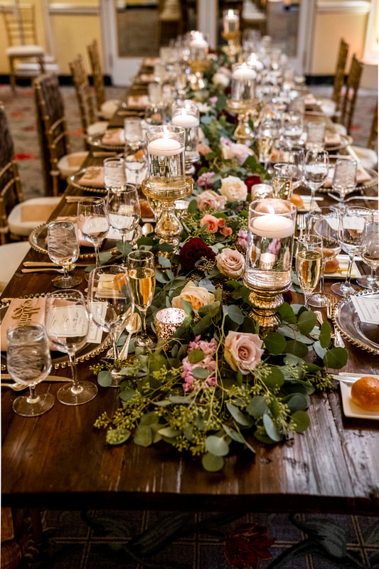 Farm table with candles and a long greenery centerpiece for a winter wedding reception