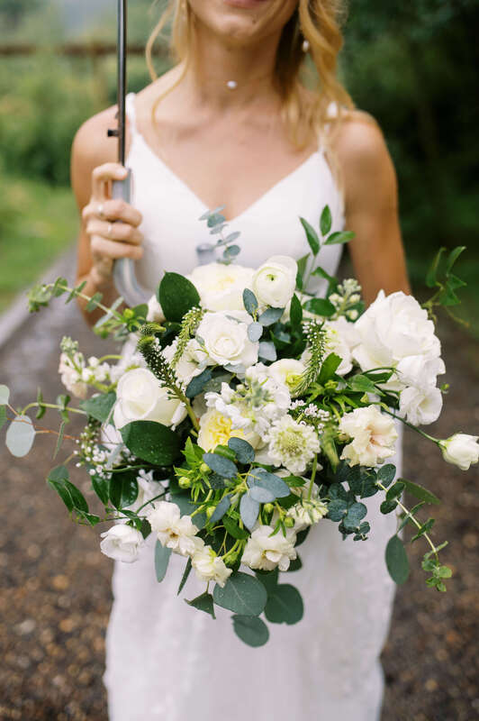 A bridal bouquet filled with white roses, snapdragons, and eucalyptus by Statice Floral