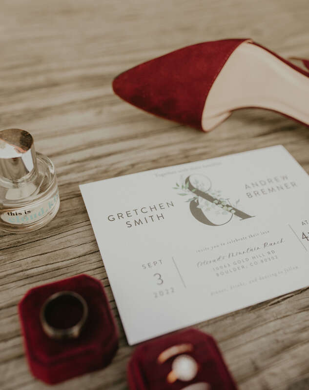 Flat lay of a wedding invitation with burgundy velvet bridal shoes