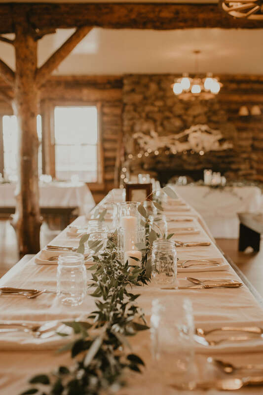 White linens and eucalyptus on a farm table at a rustic wedding reception
