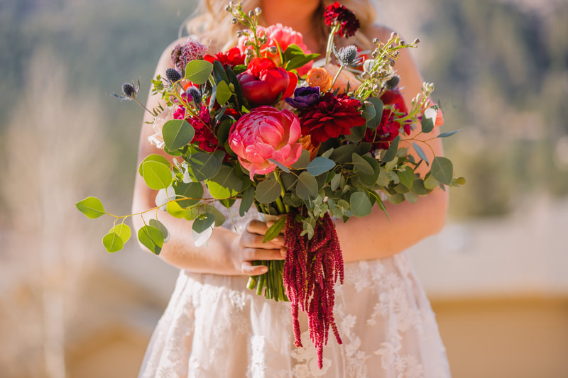 A fall bridal bouquet filled with fuchsia peonies and red dahlias by Statice Floral