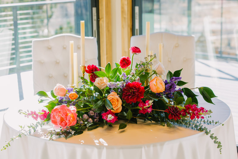 Floral centerpiece for a fall wedding reception with fuchsia peonies and red dahlias 