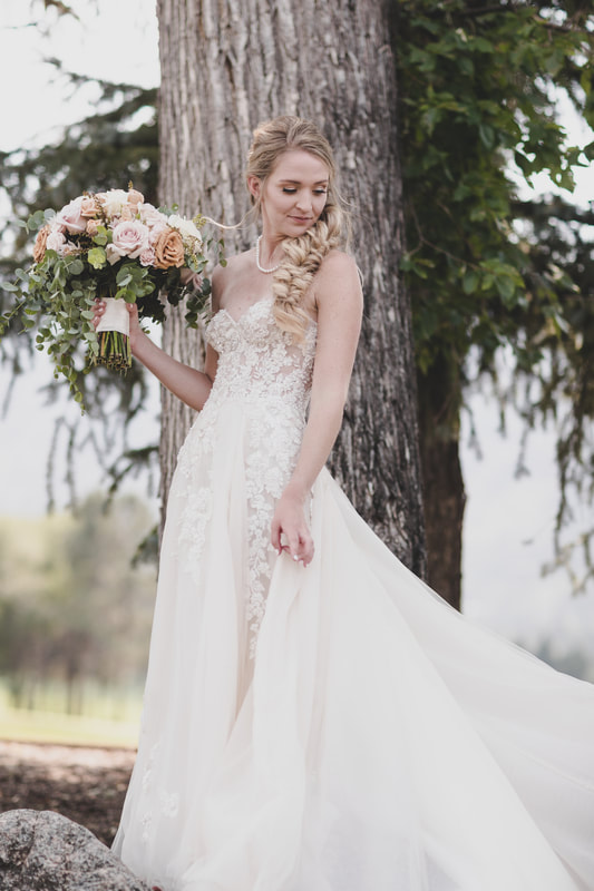 Bride with bridal bouquet in front of a tree
