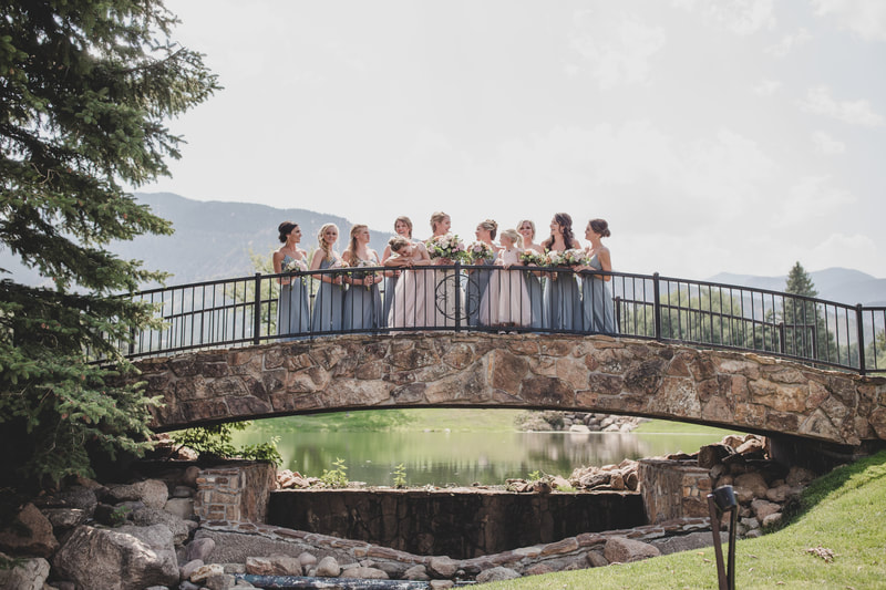 Bride with bridesmaids standing on stone bridge