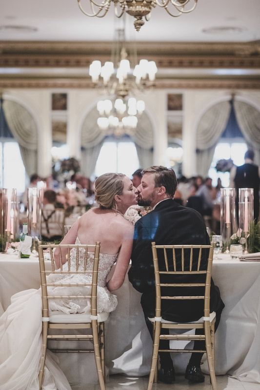 Bride and groom sharing a kiss at the sweetheart table while seated