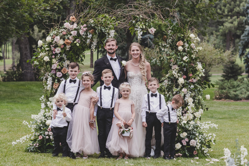Bride and groom with their ring bearers and flower girls in front of their floral altar