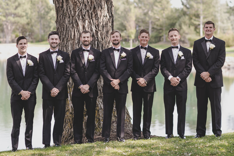 Groom and groomsmen standing in front of a large tree and The Broadmoor Lake