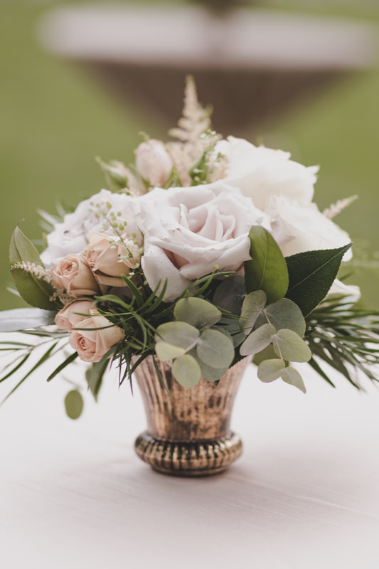 up close photo of small centerpiece with white rose, light pink roses and greenery