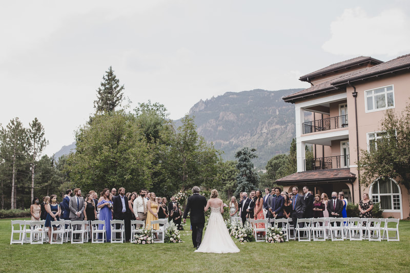 Bride and her father beginning to walk down the aisle with a view of the mountains in front of them